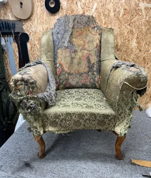 A worn floral armchair before reupholstery